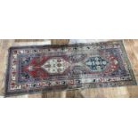 Caucasian red ground rug with geometric and foliate designs, 220cm x 87cmWorn and in need of