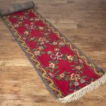 Pair of country house hall runners English, each of burgundy ground, with ribbon tie decoration,