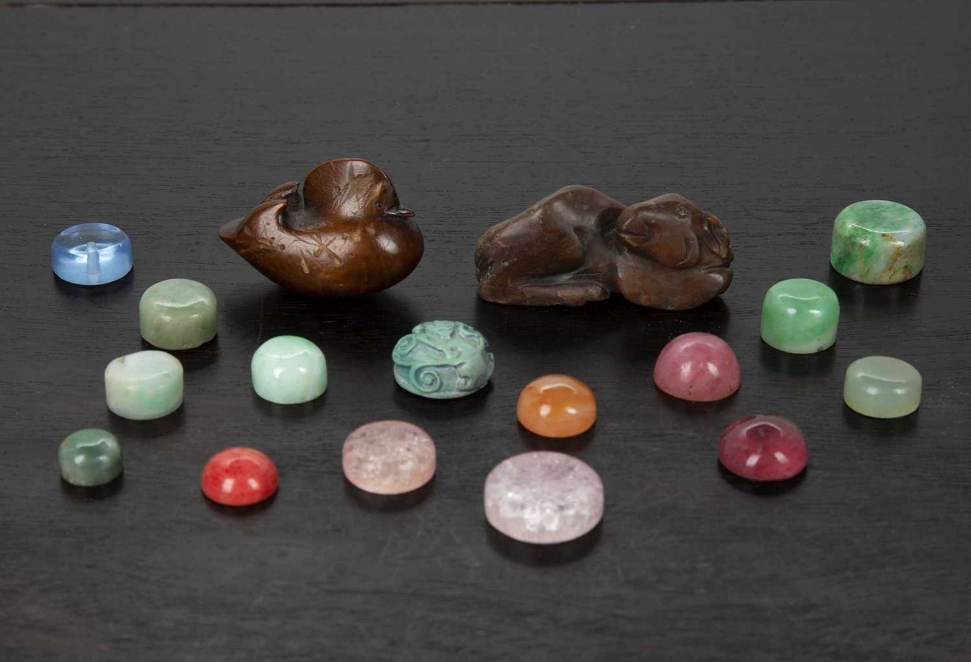 Group of snuff bottle stoppers Chinese including jade, glass and hardstone, a hardstone model ram,