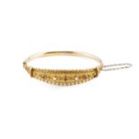 An Edwardian gem set bangle, of hinged oval form, the navette-shaped frontispiece highlighted with