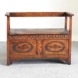 A carved oak box settle