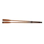 A large pair of vintage wooden rowing boat oars with brown plastic sleeves, measuring approximately