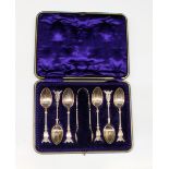 An Edwardian cased set of six silver demitasse spoons with sugar tongs with winged cherubs face