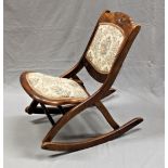 An Edwardian folding rocking chair with upholstered seat and back.