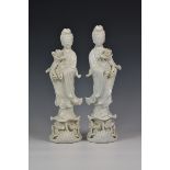 A mirrored pair of Chinese Blanc de Chine figures of Guanyin holding lotus flowers, mid to late 20th
