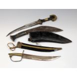 An Eastern Kukri knife in leather scabbard together with a kindjhal style knife and another. (3)