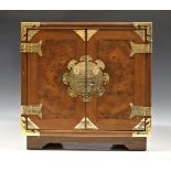 An Oriental style table cabinet with brass furniture, the hinged double opening front doors opening