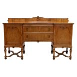 An inverted breakfront walnut sideboard, 1930s, the shaped, shell carved back over a central bank of