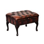 A Chesterfield buttoned red leather box footstool, the hinged top with storage beneath, on dark
