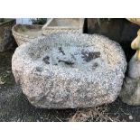 A very old Guernsey granite trough, probably 18th century, of rounded form with shallow well,