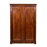 A Victorian two door figured mahogany wardrobe, the moulded cornice over two arched panelled