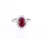 An 18ct white gold, ruby and diamond cluster ring, the approx. 3.05ct cabochon cut ruby of dark