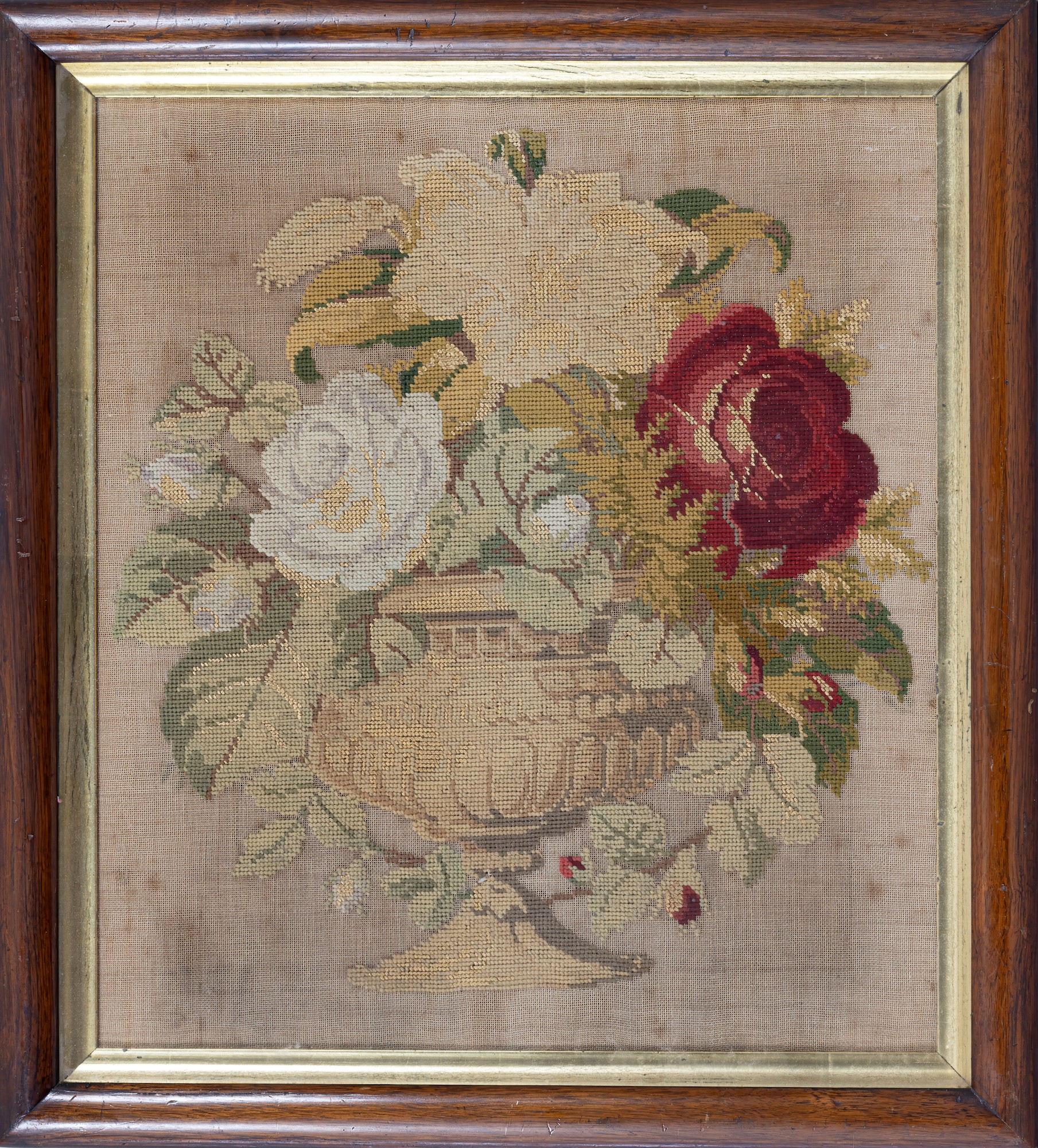 A Victorian petit point needlework, of roses in a stone urn, 17 x 15in. (43.2 x 38cm.), within a