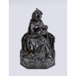 A carved ebony figure of Madonna and child, the figure seated, feeding child, the base depicting