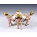 A German Schierholz porcelain figural compote or table centrepiece, the shaped bowl, with pierced