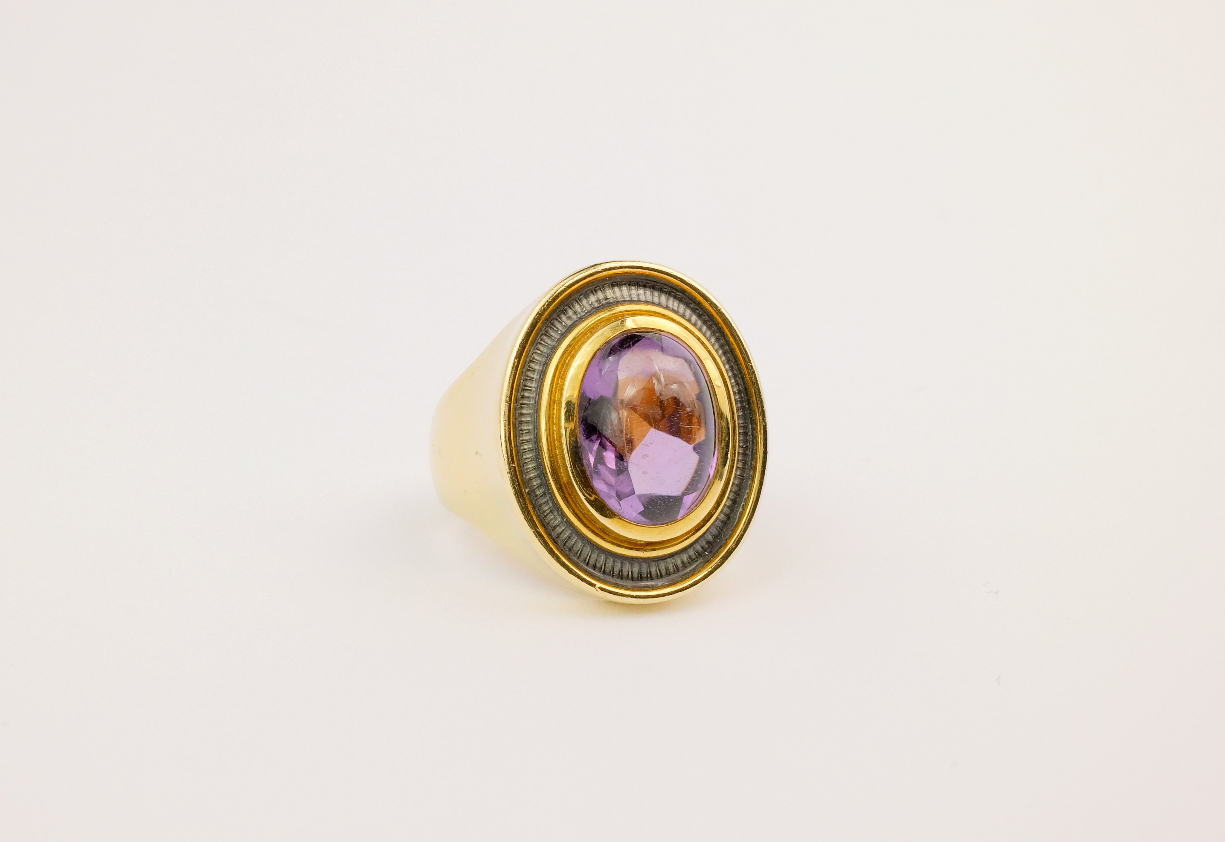 An 18ct gold, amethyst and enamel ring by Leo de Vroomen, the oval cabochon-cut amethyst within a