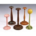 A collection of five wooden wig stands, to include a turned box wood version, one with an apple