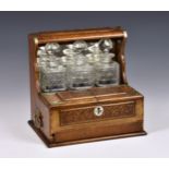 A Victorian brass mounted oak three-bottle tantalus, having mirrored panel back with compartments