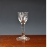 An 18th century wine glass, the ovoid bowl with bird and bud decoration, on a plain, slightly