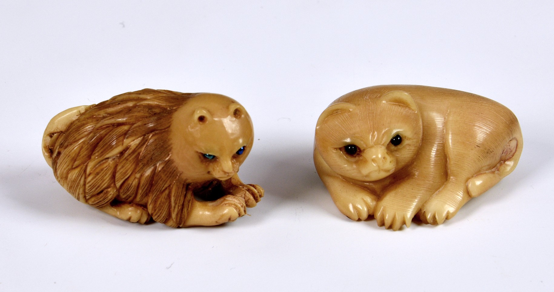 Two Japanese Tagua Nut Netsuke fashioned as cats, having glass eyes, both signed, 1 ¾in. (4.5cm.)