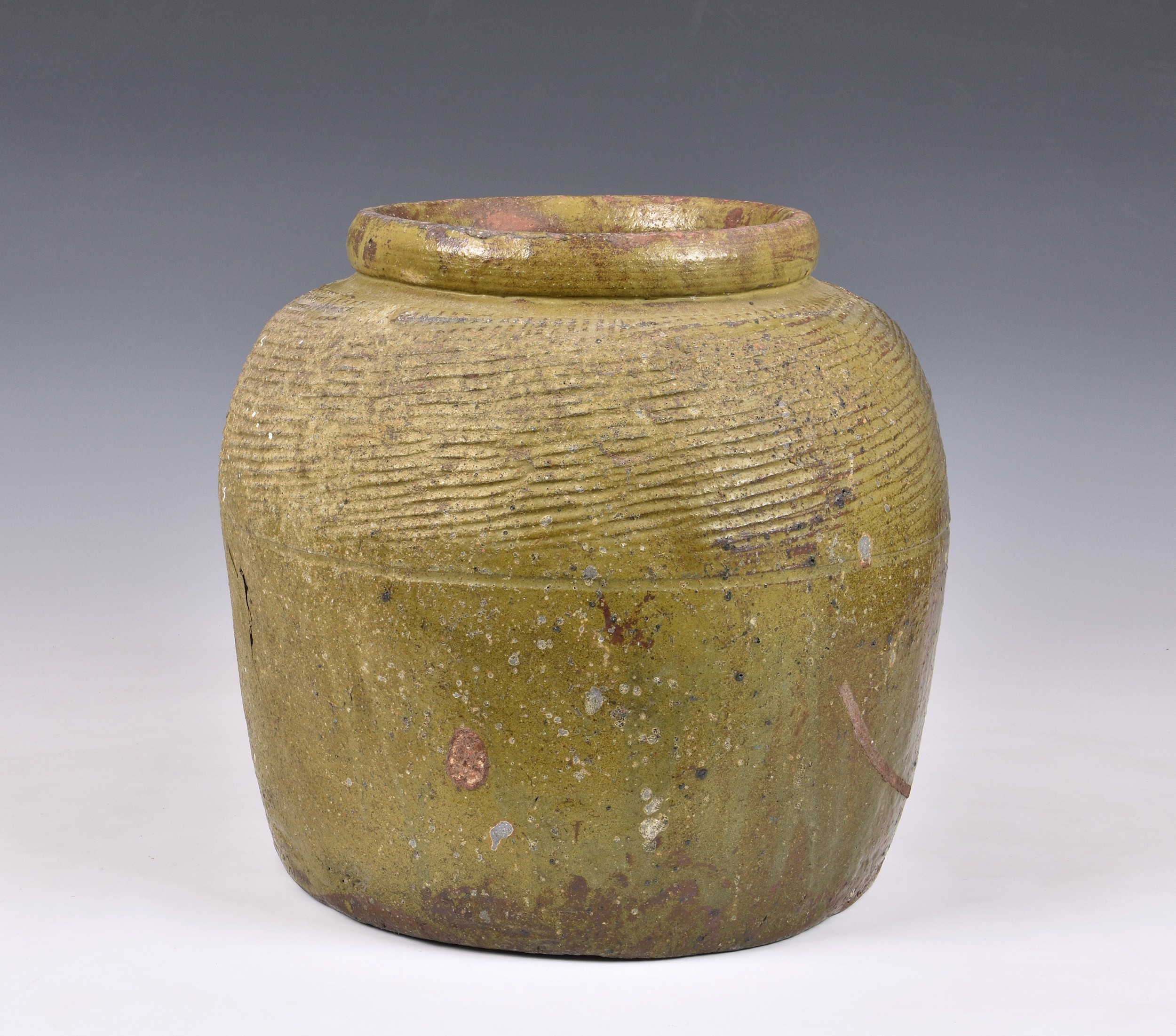 A large antique olive green glazed stoneware jar, with old crack repair, 12in. (30.5cm.) high.