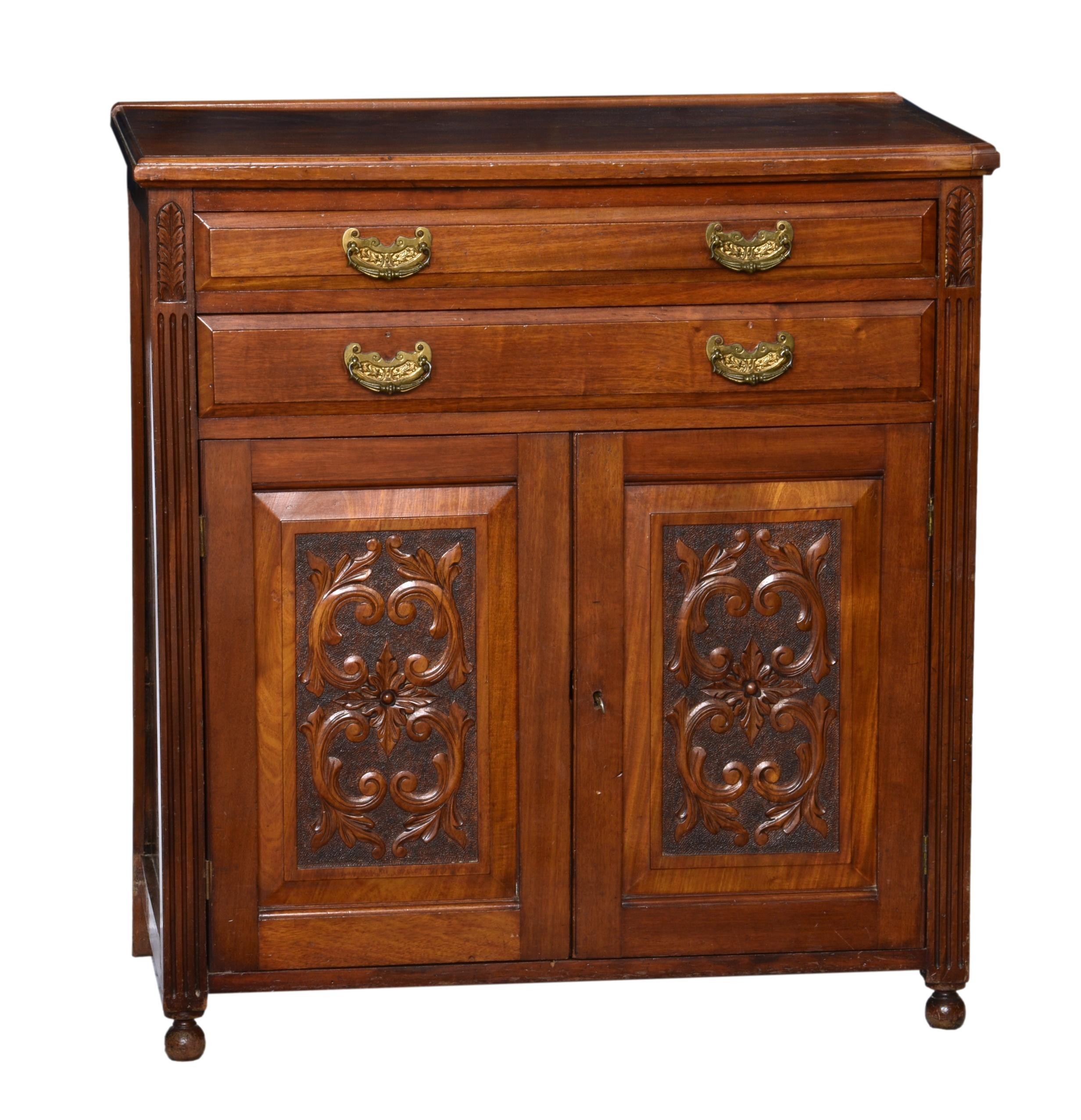 An Edwardian carved walnut side cabinet, the moulded top over two bevelled drawers with decorative