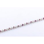 An 18ct white gold, ruby and diamond line bracelet, with alternating round cut rubies and