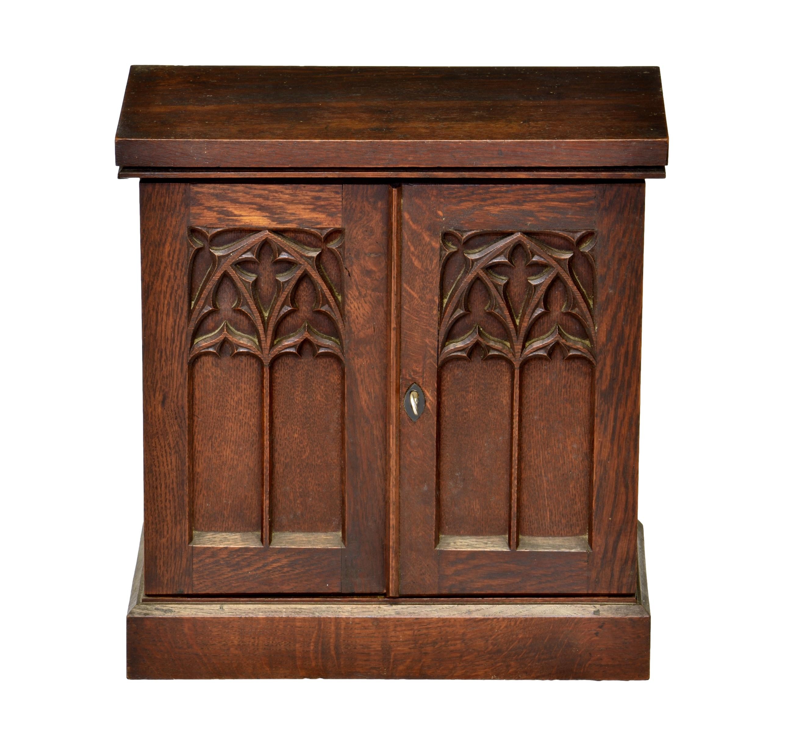 A Victorian Gothic Revival oak table cabinet, the Gothic window panelled doors enclosing a fitted