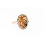 A modernist 9ct yellow gold and moss agate ring, 1970s-80s, the oval disc of moss agate held in a