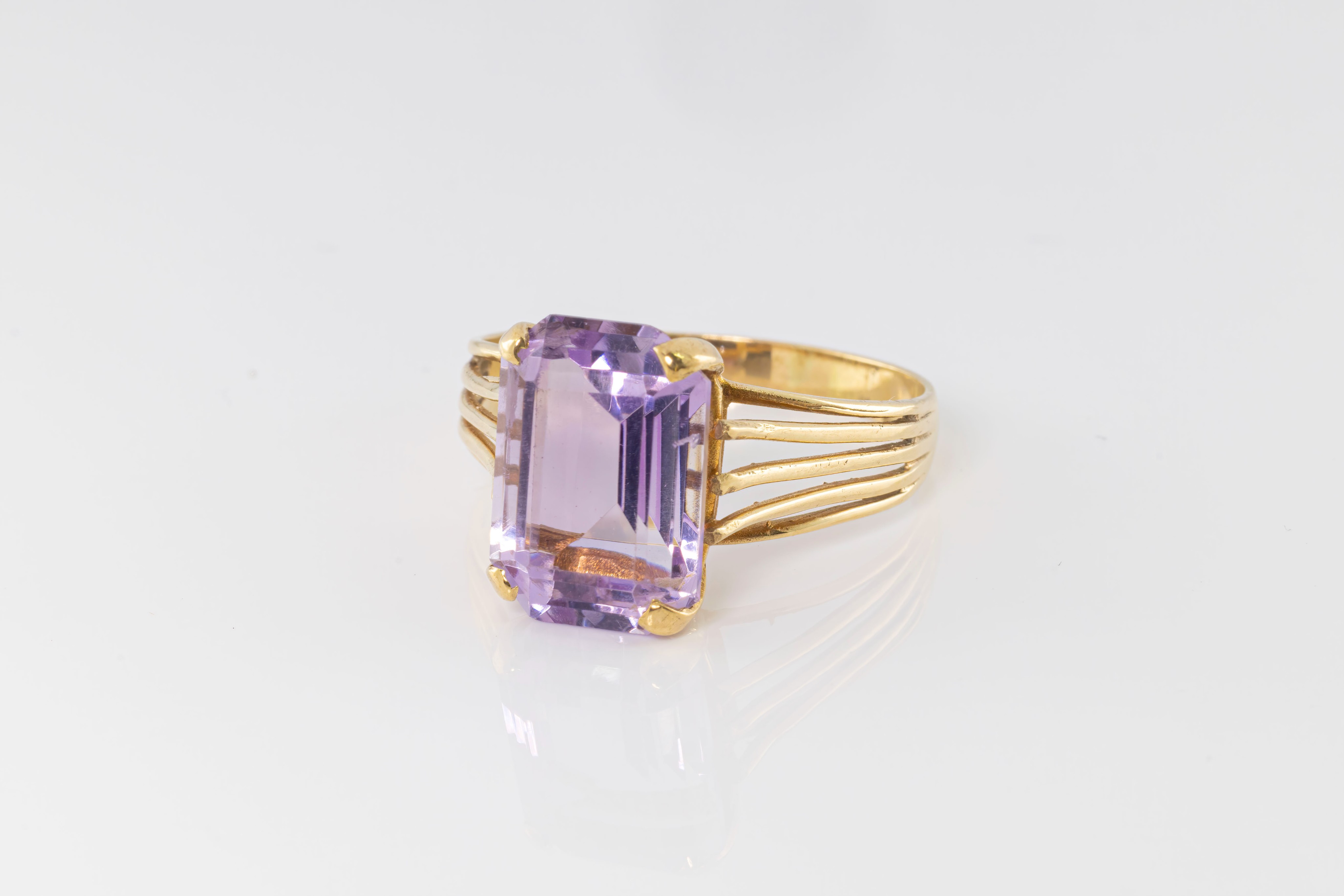 A 9ct gold and pale amethyst dress ring, the emerald cut amethyst over split shoulders, size S..