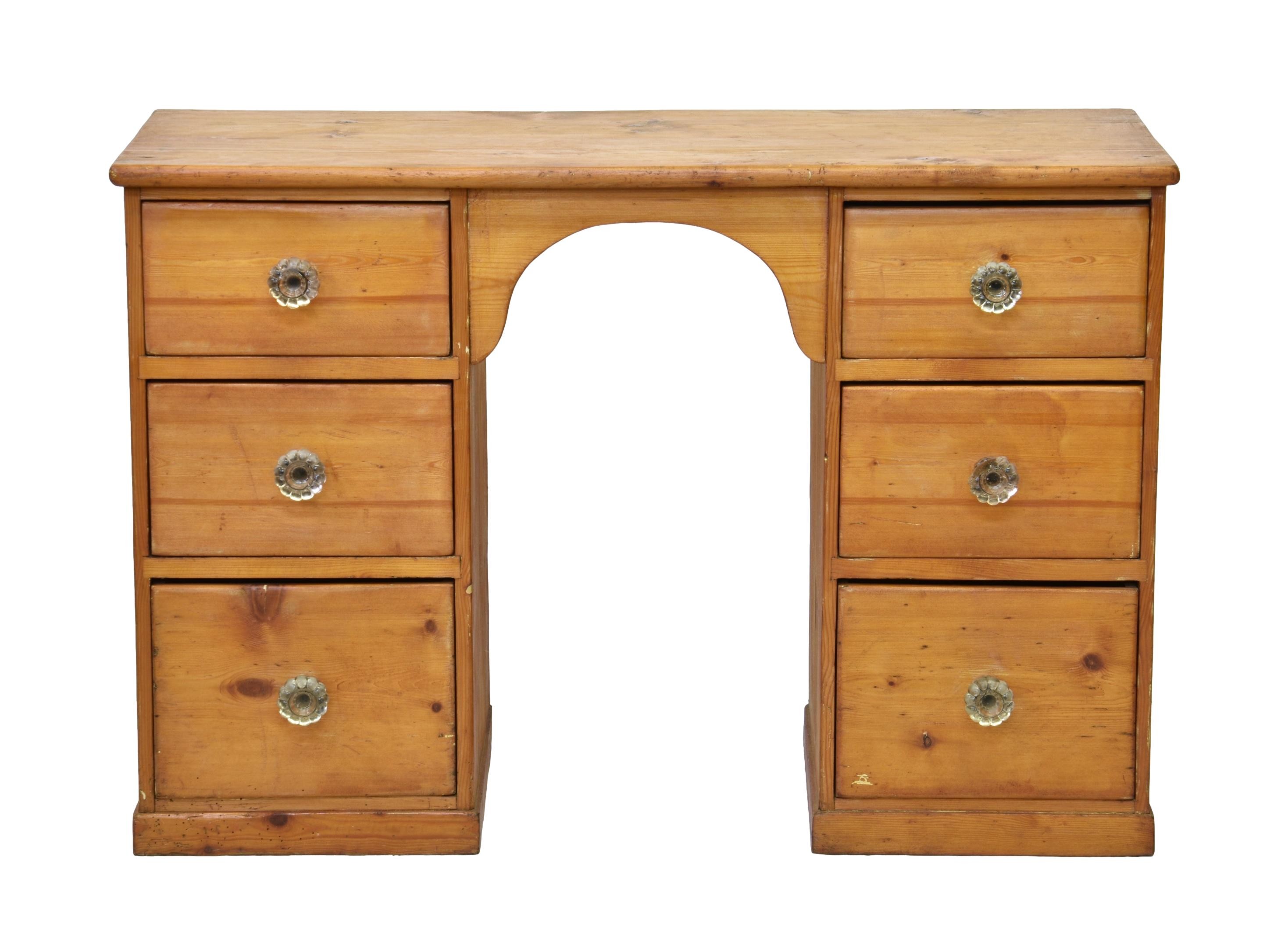 An early 20th century pine kneehole desk, the arched kneehole flanked by two banks of three