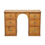 An early 20th century pine kneehole desk, the arched kneehole flanked by two banks of three