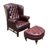 A red leather wingback armchair with studded scroll arms with matching foot stool