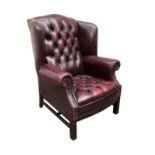A red leather wingback armchair with studded scroll arms