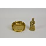 A polished bronze figural table bell, of an elderly priest holding a stomach warmer and several