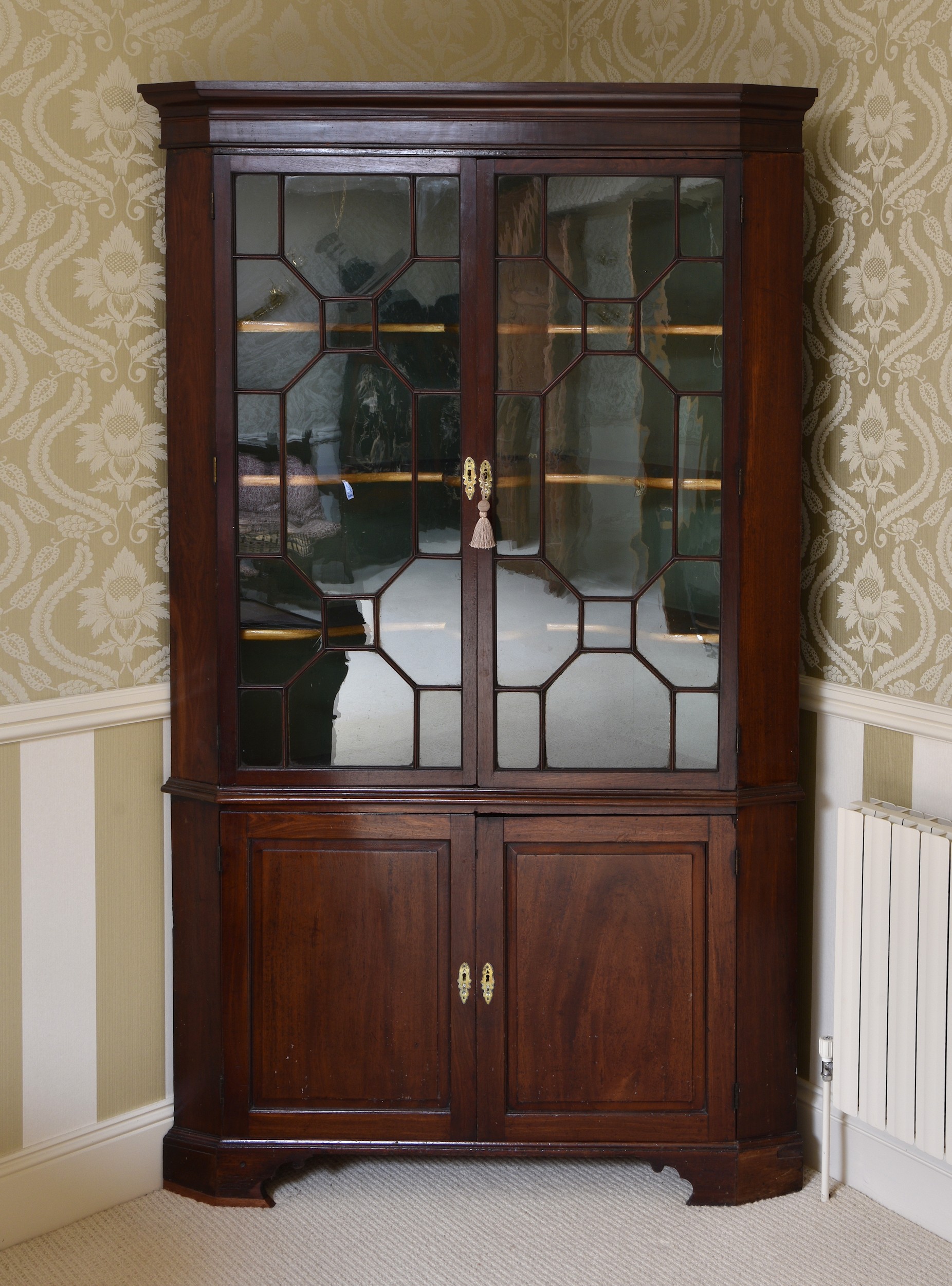 A large George III part-glazed mahogany floorstanding corner cupboard, of imposing proportions,