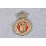 A Royal Guernsey Light Infantry cap badge / helmet plate, Guernsey Arms encompassed by belt