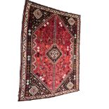 A Persian style rug on red ground, the central floral medallion surrounded by bird and floral