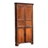 A George II two piece floor standing red walnut corner cupboard, the reel moulded cornice over a