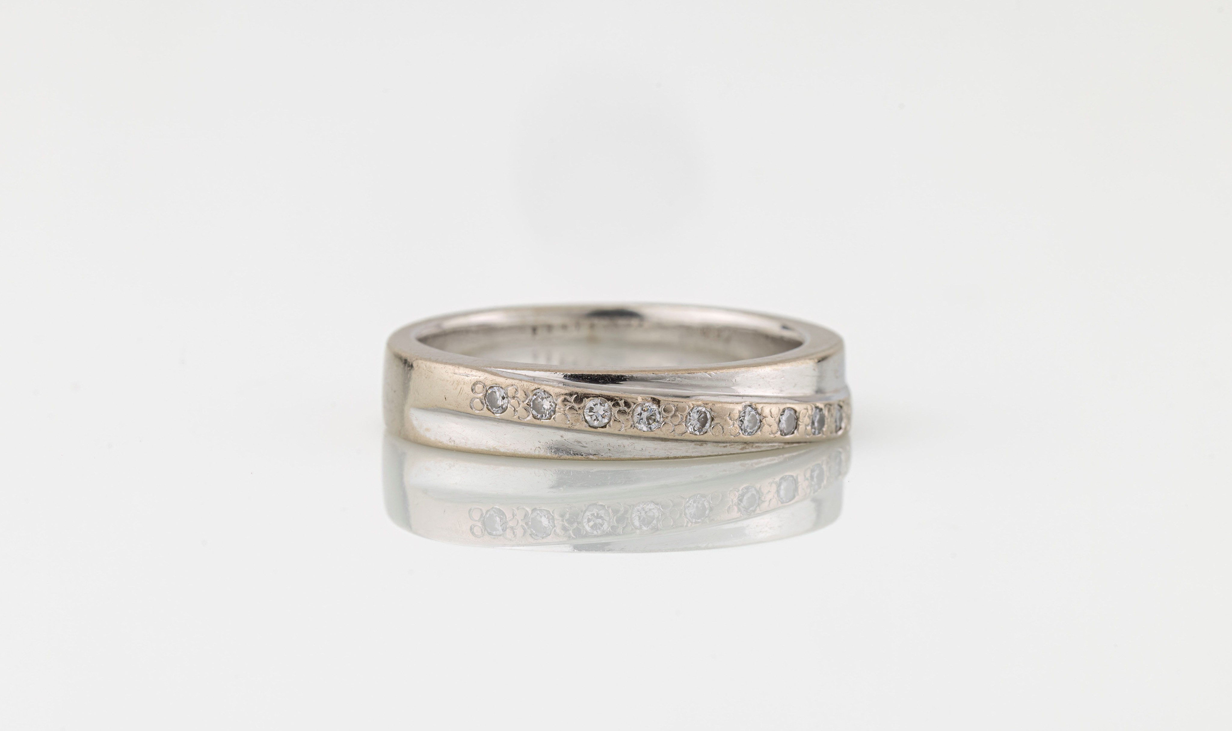 An 18ct white gold and diamond half eternity ring, the broad band twist-set with a row of nine
