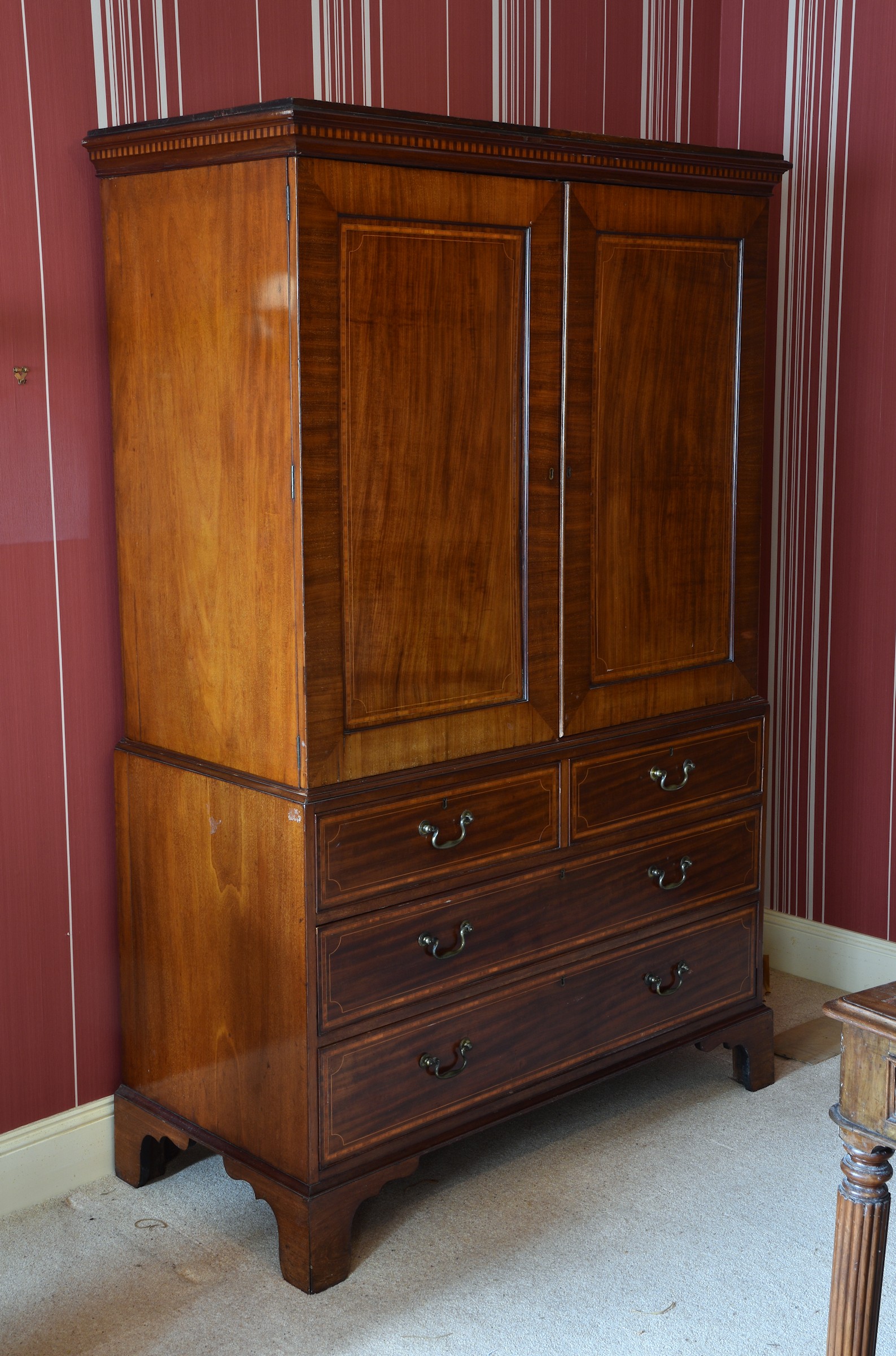 A late Regency inlaid mahogany linen press, the dentil banded cornice over two panelled, satinwood
