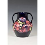 A large Moorcroft twin handled Pottery vase, Walter Moorcroft, 'anemone' pattern on dark blue