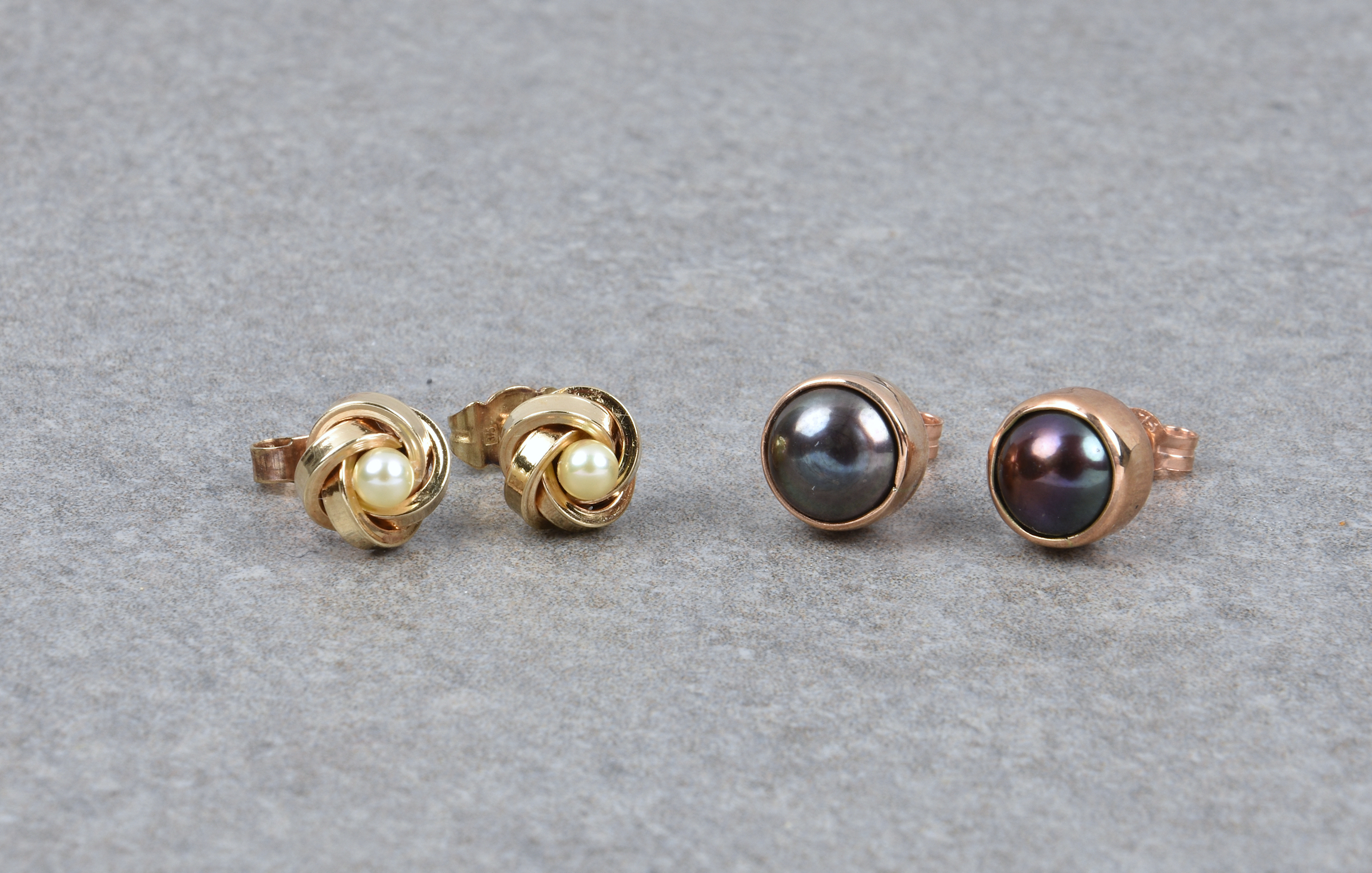 Two pairs of 9ct gold and pearl stud earrings, comprising a pair of rose gold and black pearl studs;