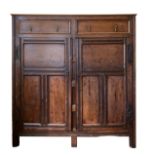An 18th century and later tall, shallow oak panelled cabinet, the plain top over three panelled