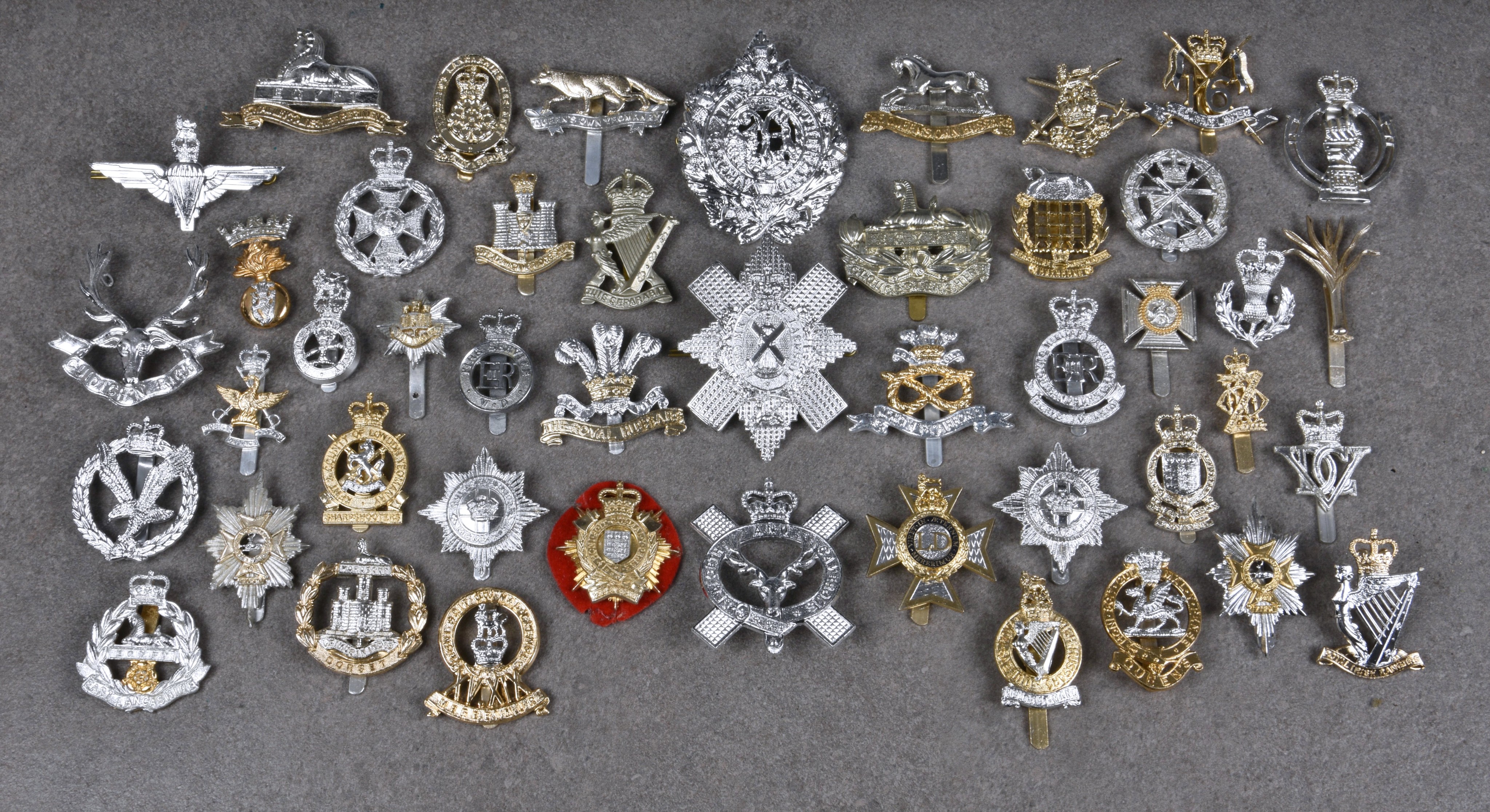 A collection of various Military anodised aluminium cap badges etc, to include Queens Own