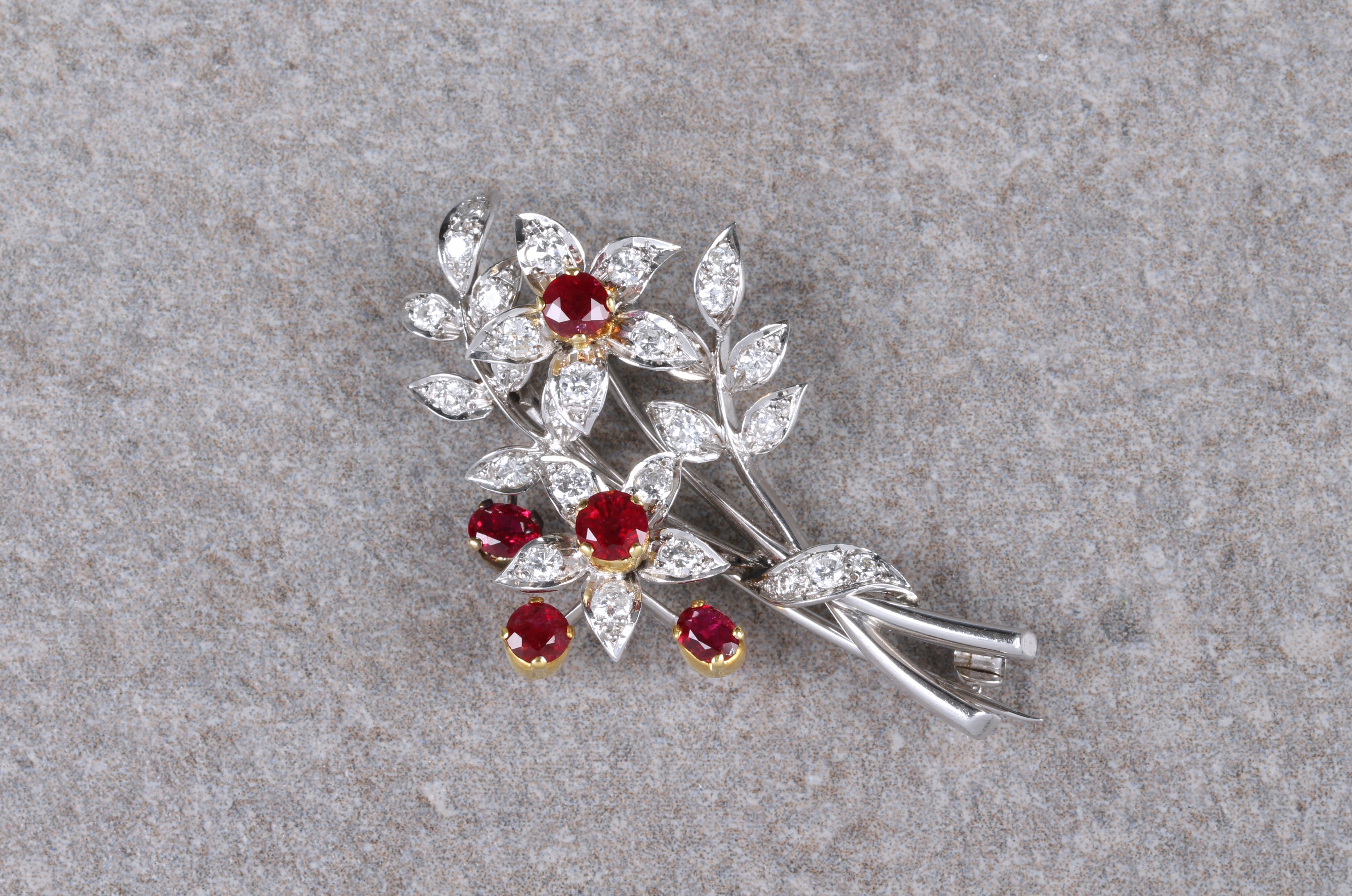 An 18ct two colour gold, ruby and diamond floral spray brooch, with five round cut rubies in