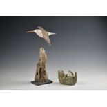 A decoy style carved and painted wooden sculpture of a curlew in flight, on a driftwood stand with
