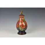 A Moorcroft flambe glazed lamp, baluster form, in the Fresia pattern on a rust red and blue flambe