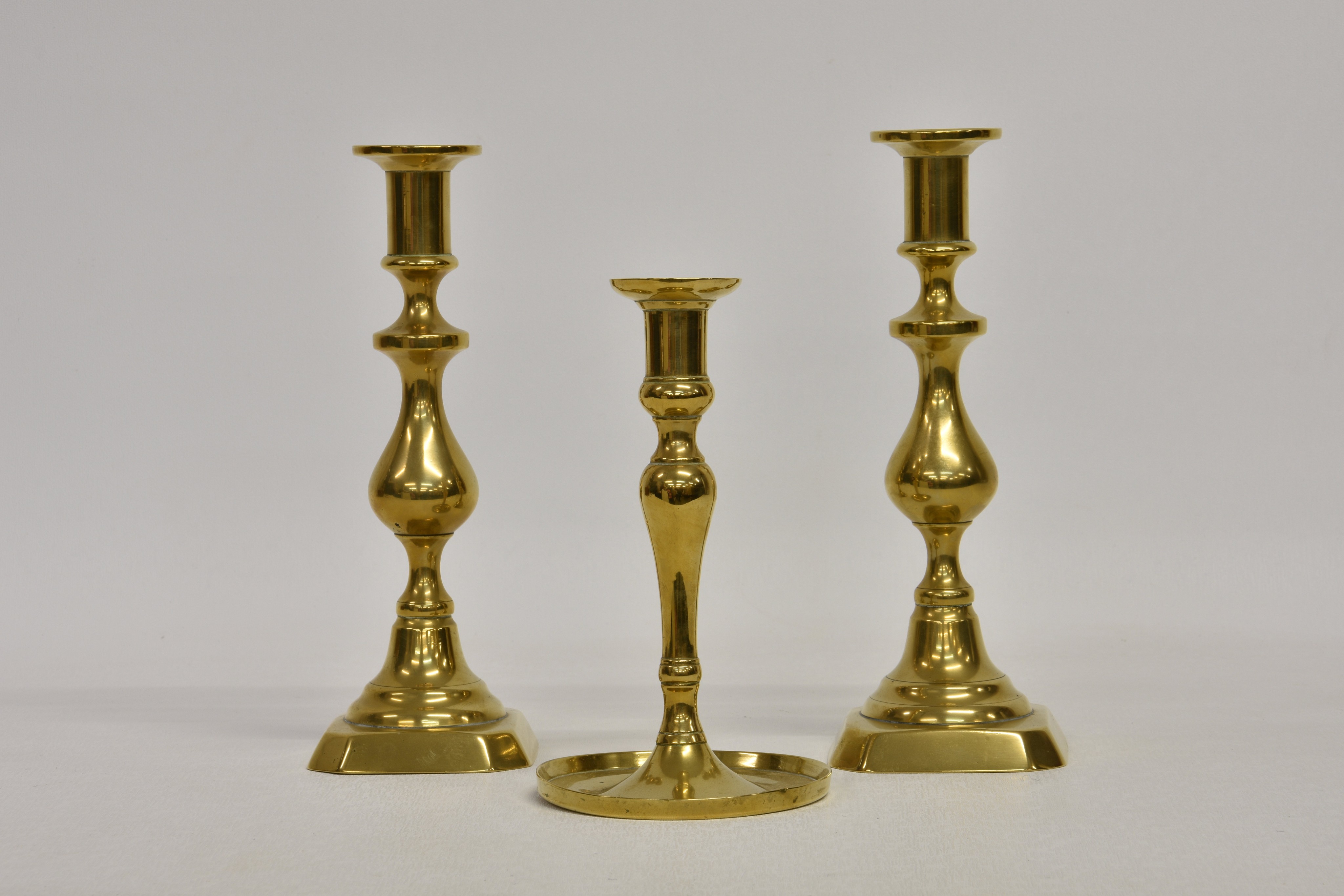 A pair of Victorian brass candlesticks, on knopped baluster stems and clipped square step bases