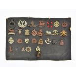 A collection of twenty seven military cap & collar badges, mounted on board, to include WW1 New